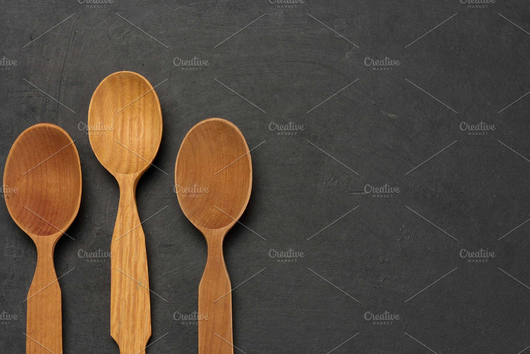 Empty wooden spoons on a dark board, top view, a Food & Drink Photo by ndanko