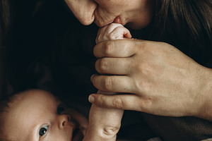 Happy Mother kissing cute little baby hand on bed close up. Happ, a Person Photo by Sonjachni