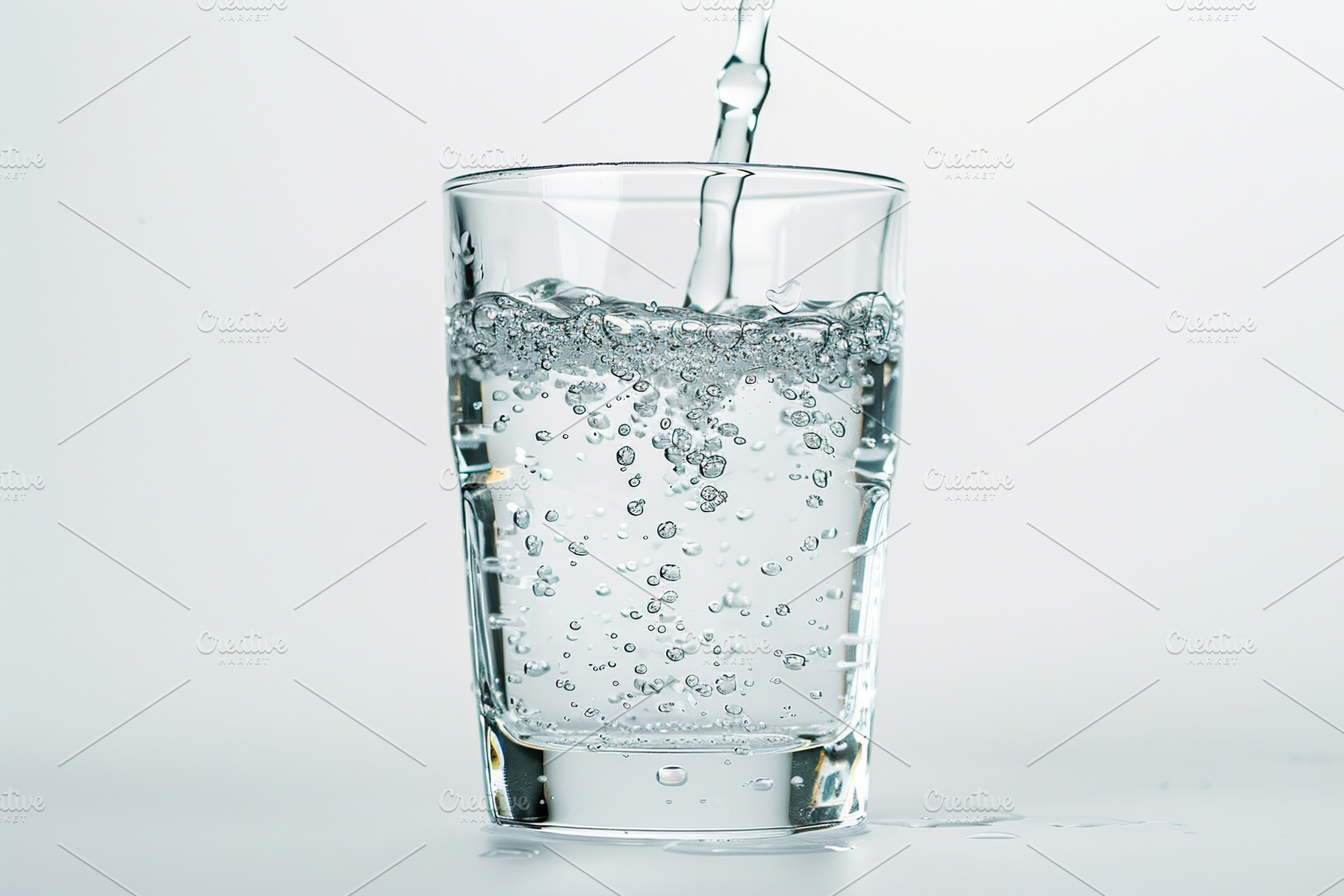 Pouring water into glass on white background, a Photo by AlyaAnd