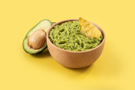 Mexican guacamole with nacho chip on yellow background, a Food & Drink Photo by etorres69