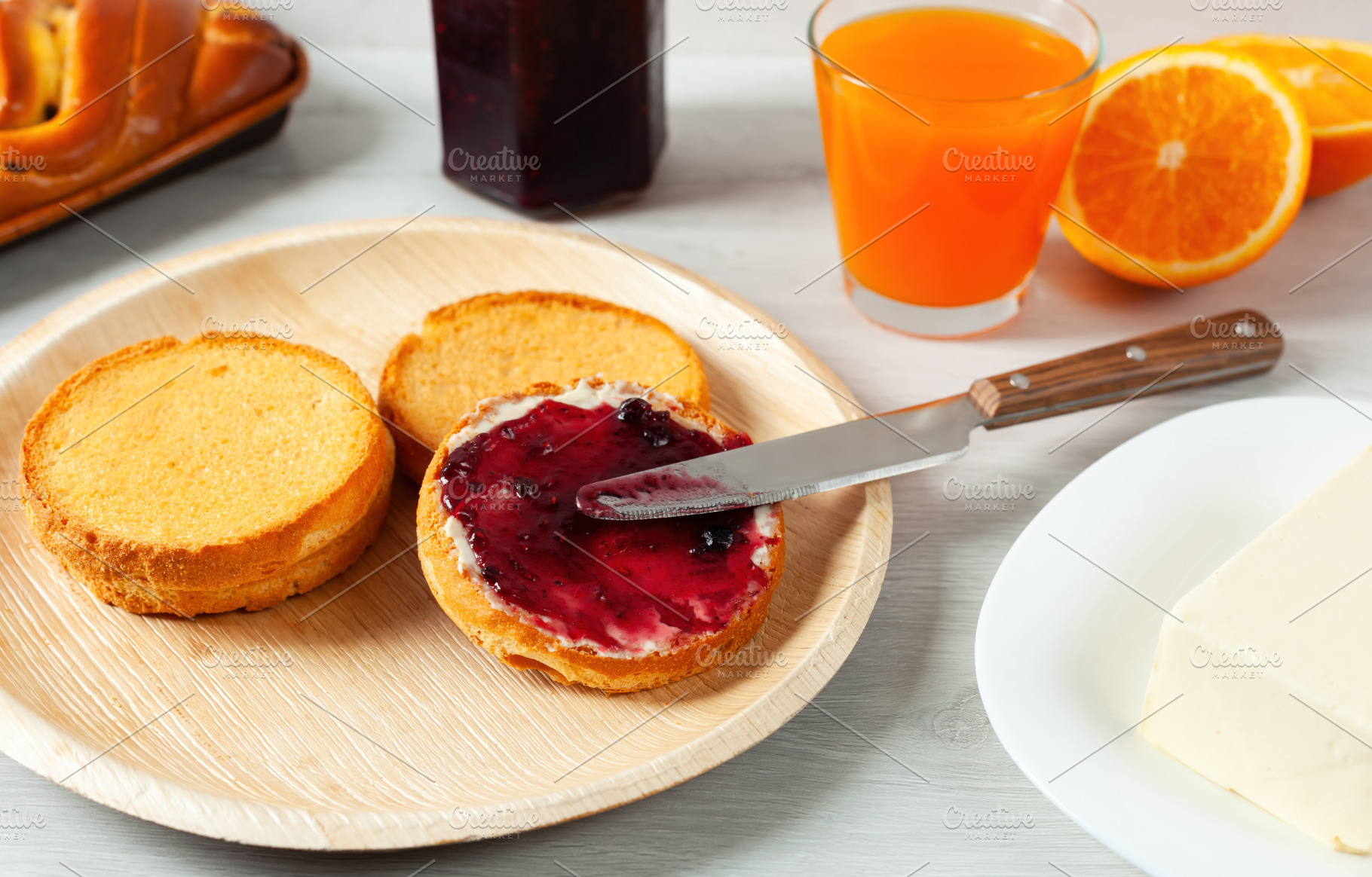 Spreading blueberry jam on toasted bread for breakfast with orange juice and bu, a Food & Drink Photo by Antonio Gravante Market