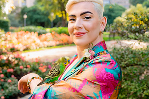 Trans woman with budgerigar at urban park, a Person Photo by DanFLCreativo