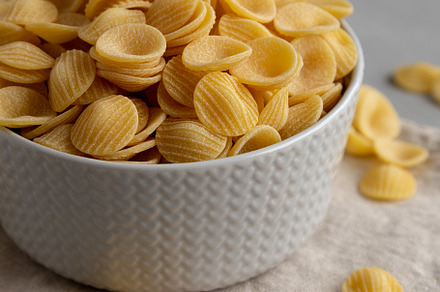 Dry, Uncooked Orecchiette Pasta in a Bowl, side view. Close-up., a Food & Drink Photo by LiudmylaChuhunova