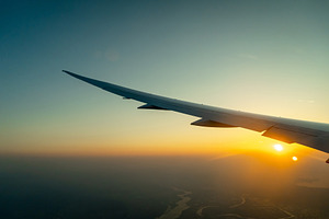 Airplane wing above Osaka coast during sunset descent flight, a Transportation Photo by GoodGoods