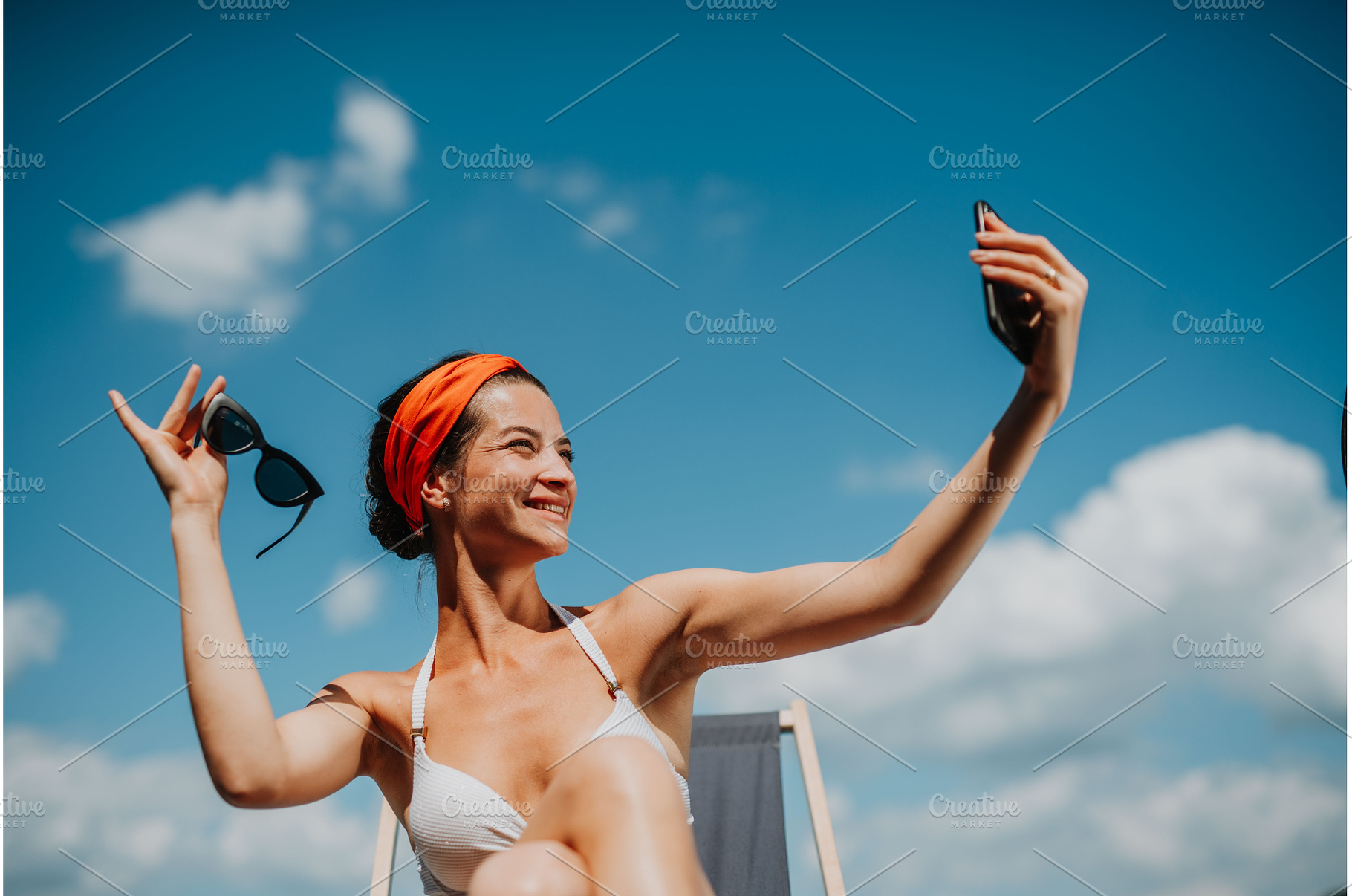 Young woman sitting by swimming pool, a Person Photo by HalfPoint