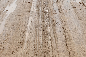 Dirty road after rain with car marks