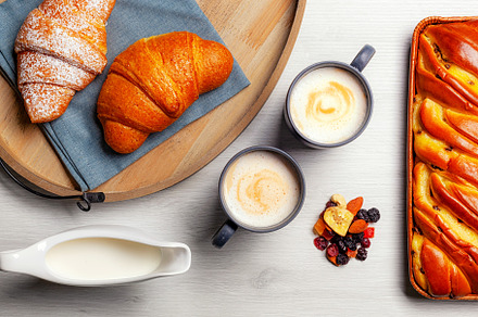 Delicious breakfast with croissants, cappuccino, milk, dried fruit and sweet br, a Food & Drink Photo by Antonio Gravante Market