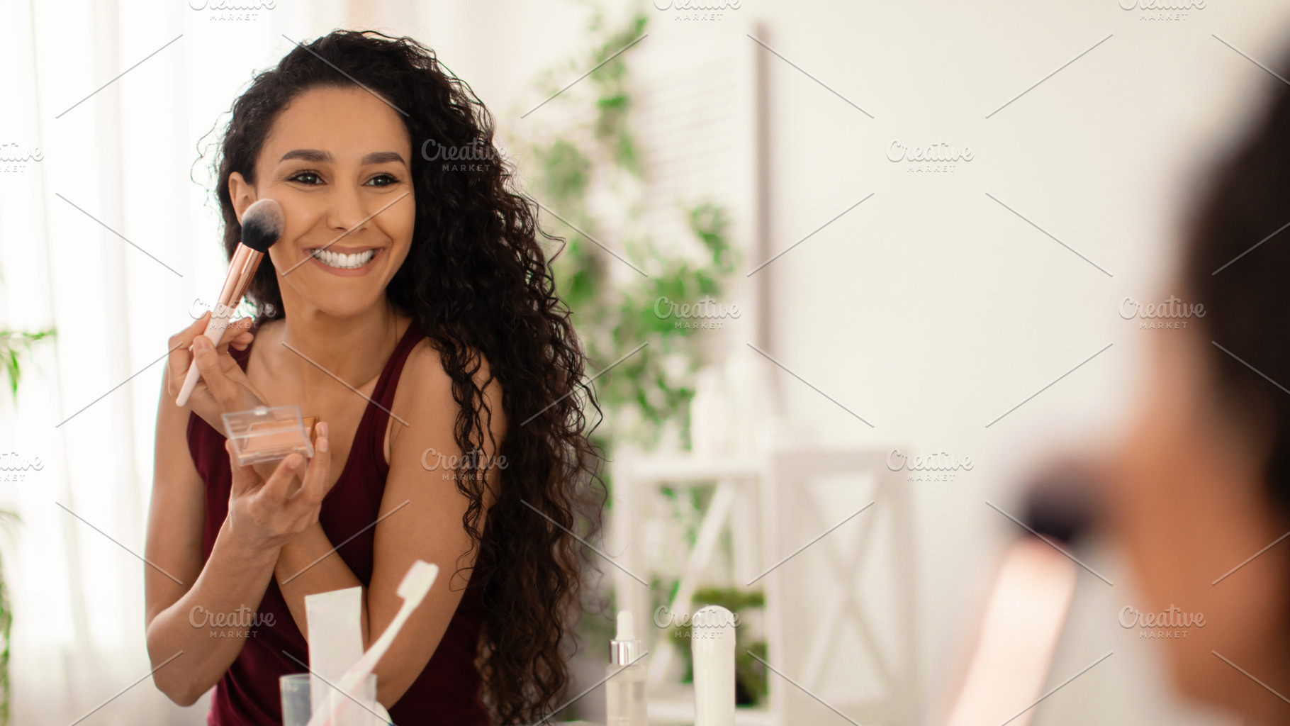 Cheerful young woman applying powder with brush, using decorative makeup in fro, a Photo by Prostock-Studio