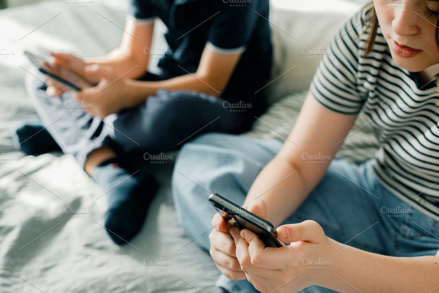 Teen girl and boy 7-8 years using mobile phone app playing game at home, a Person Photo by Anikona