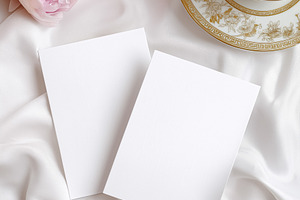 Two blank vertical cards arranged on white silk fabric with pink peonies and an, a Holiday Photo by Studio ANNA
