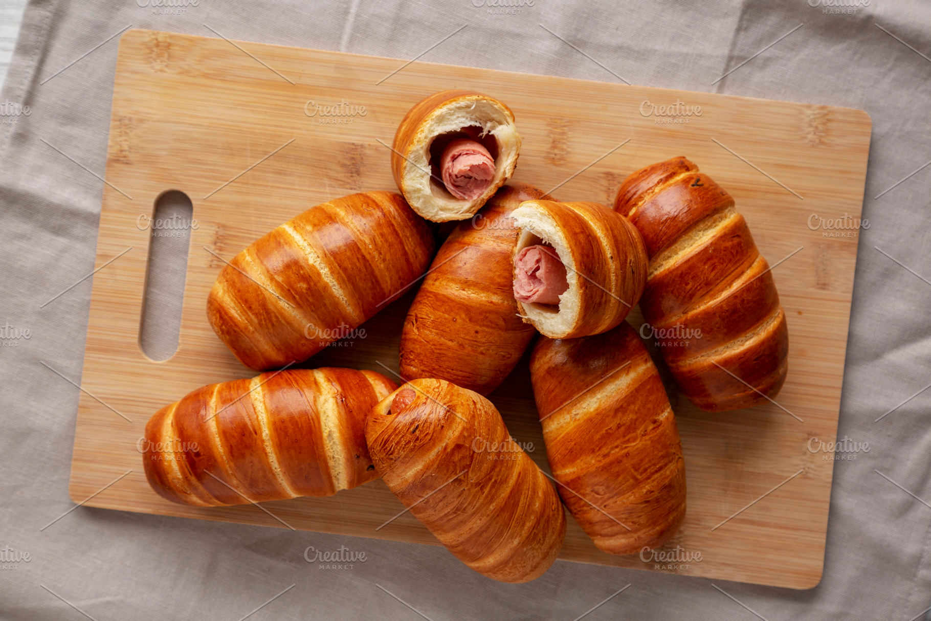 Homemade Sausage Buns on a bamboo board, top view. Flat lay, ove, a Food & Drink Photo by LiudmylaChuhunova