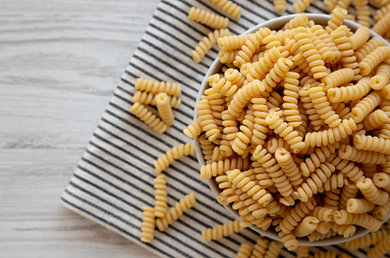 Uncooked Organic Dry Fusilli Pasta in a Bowl, top view. Flat lay, a Food & Drink Photo by LiudmylaChuhunova