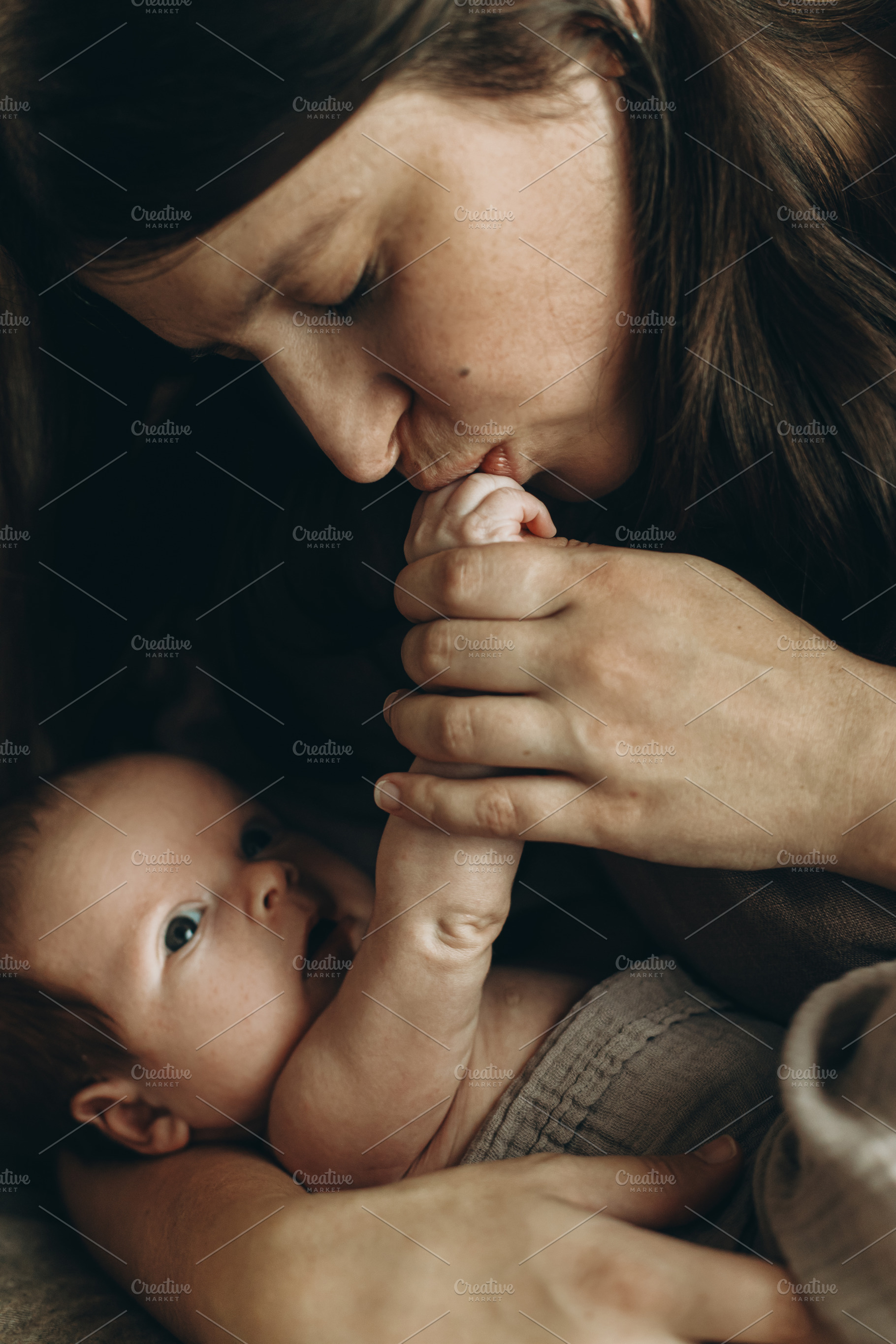 Happy Mother kissing cute little baby hand on bed close up. Happ, a Person Photo by Sonjachni