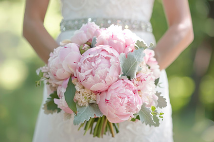 The bride stands outdoors, gently ho, a Photo by Tanuart