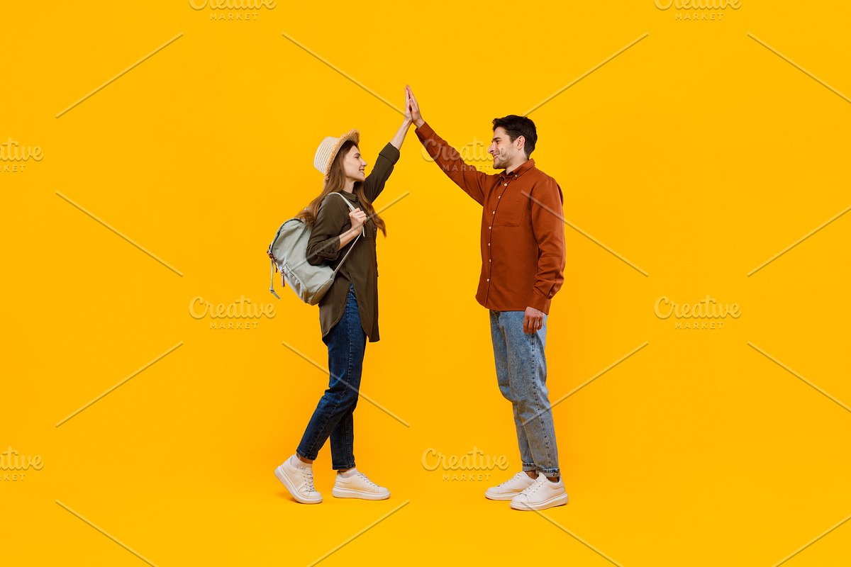 Happy Tourists Couple Giving High Five Standing Over Yellow Background, a Photo by Prostock-Studio (Photo 2 of 2)