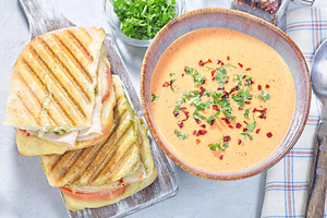 Red bell pepper cream soup served with grilled turkey panini, horizontal top vi, a Food & Drink Photo by iuliia_n