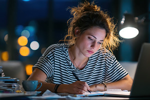 Young woman studying late at night w, a Photo by Pixeness Studio