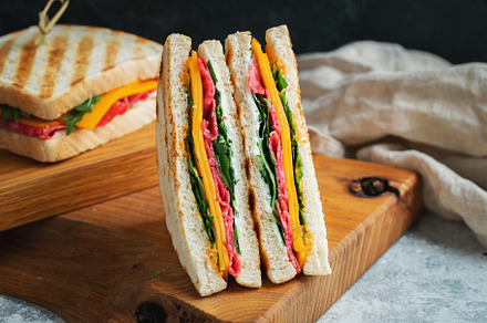 Two homemade sandwiches with sausage, cheese and arugula on a light concrete ba, a Food & Drink Photo by Budarinphoto