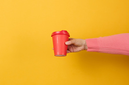 hand holds paper cardboard red cup for coffee, yellow background, a Food & Drink Photo by ndanko