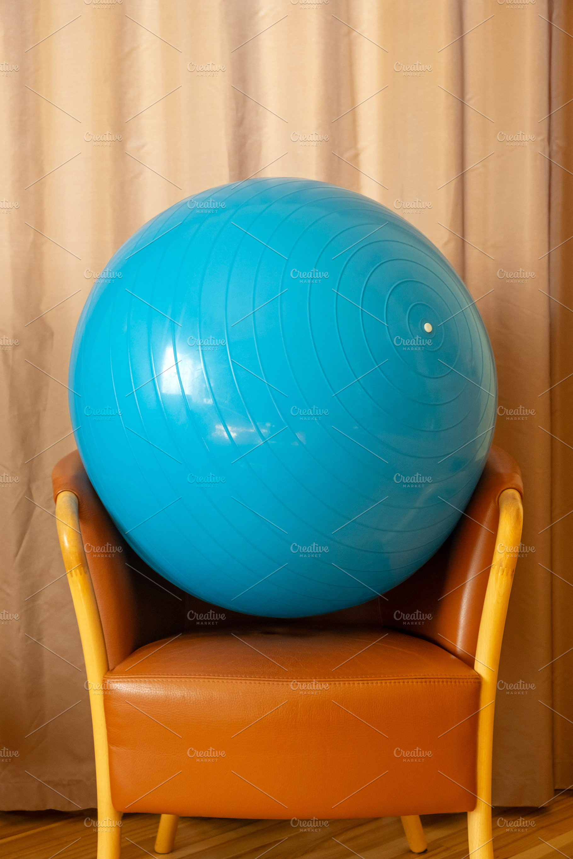 Blue gym ball rests on the armchair, a Sports & Recreation Photo by BOOCYS
