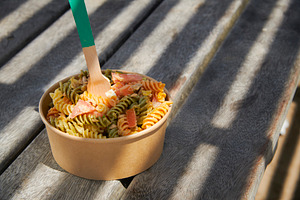 pasta salad served in a brown paper takeout bowl, a Photo by Nito