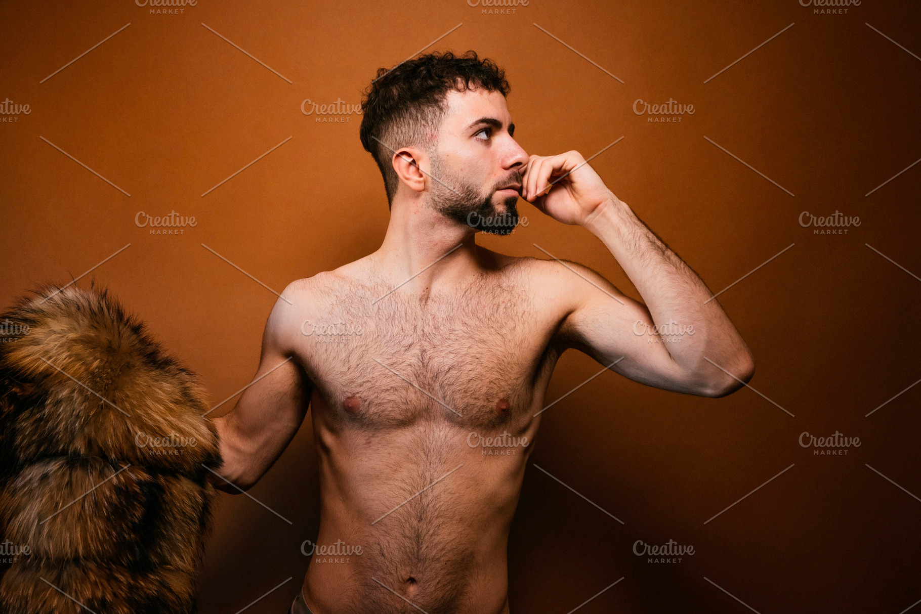 Young adult man posing with fur coat on shoulder in studio, a Photo by karrastock