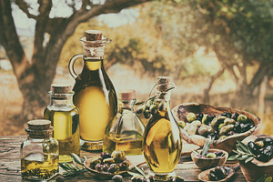 Bottle of craft farm olive oil stands on a wooden table, behind, a Food & Drink Photo by Volff