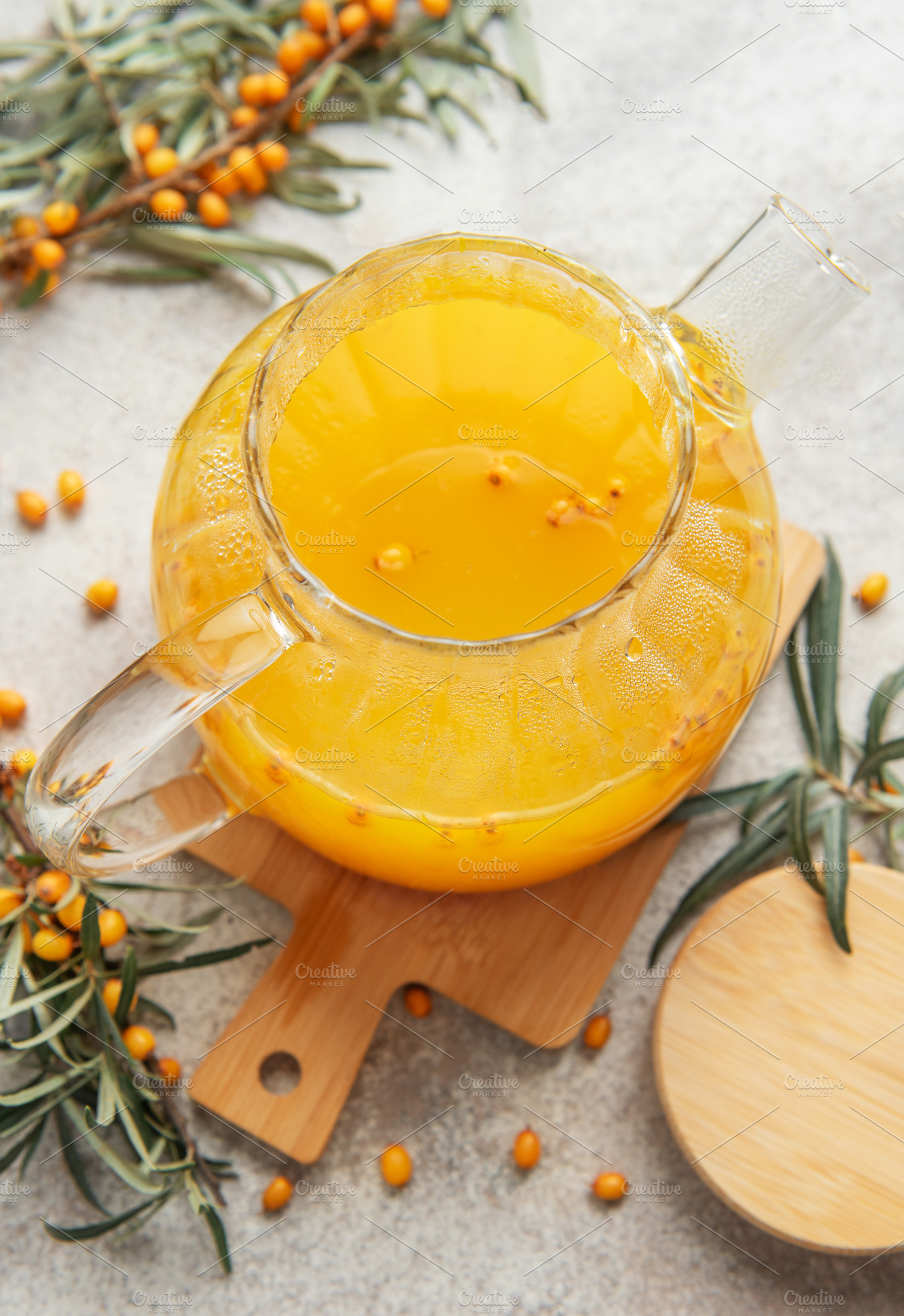 Steaming sea buckthorn tea brewing in glass teapot on wooden boa, a Food & Drink Photo by Olena Rudo