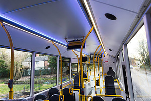 Interior of a modern Manchester bus with yellow poles and blue lighting during, a Photo by AS photostudio