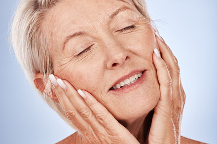 Woman, face and closed eyes for skincare beauty or relax natural skin wellness in studio. Luxury cosmetics makeup, hands on facial treatment or healthy, anti aging and skin botox or body lifestyle, a Photo by Peopleimages.com