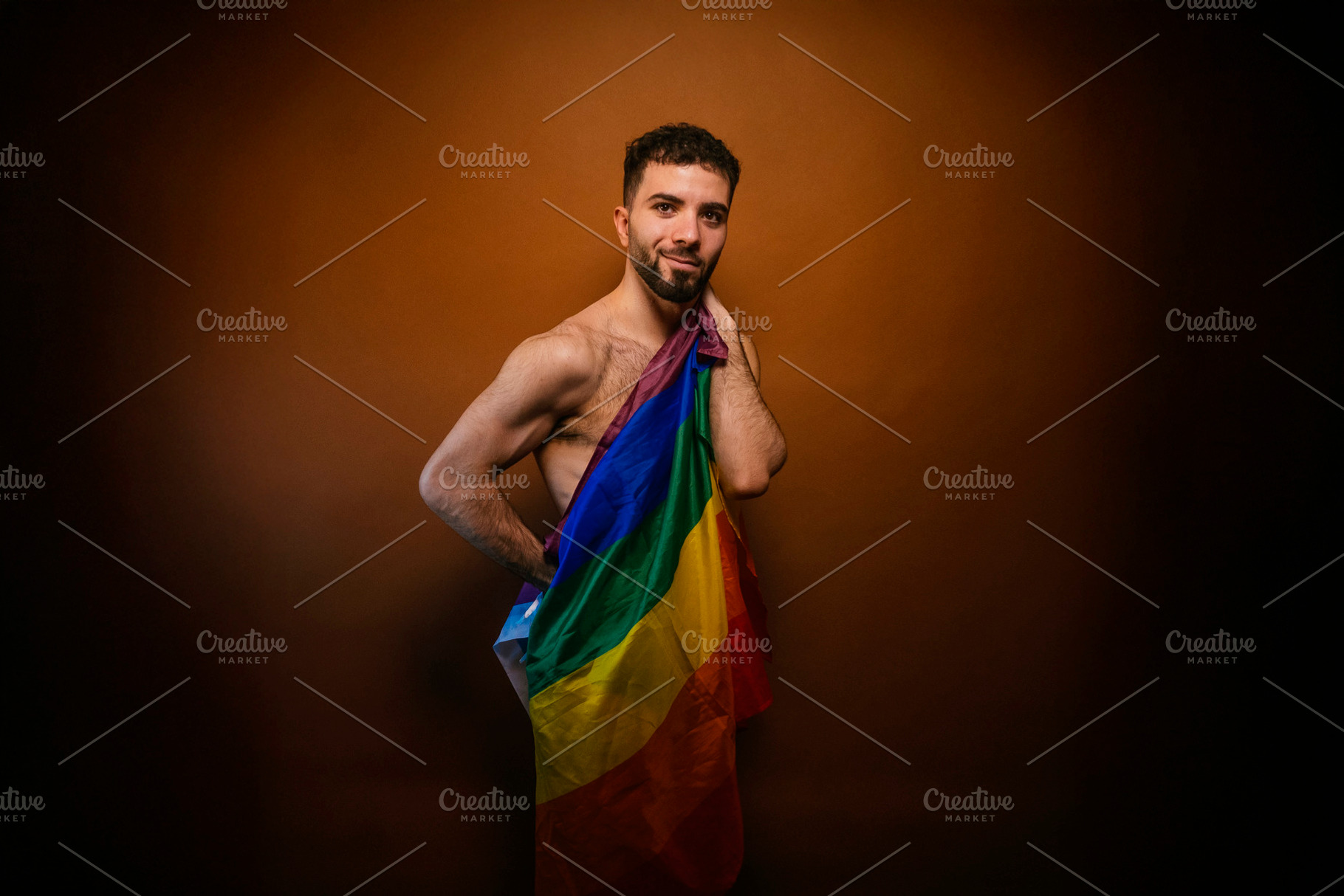 Young man proudly holding rainbow flag celebrating lgbtq+ pride, a Photo by karrastock