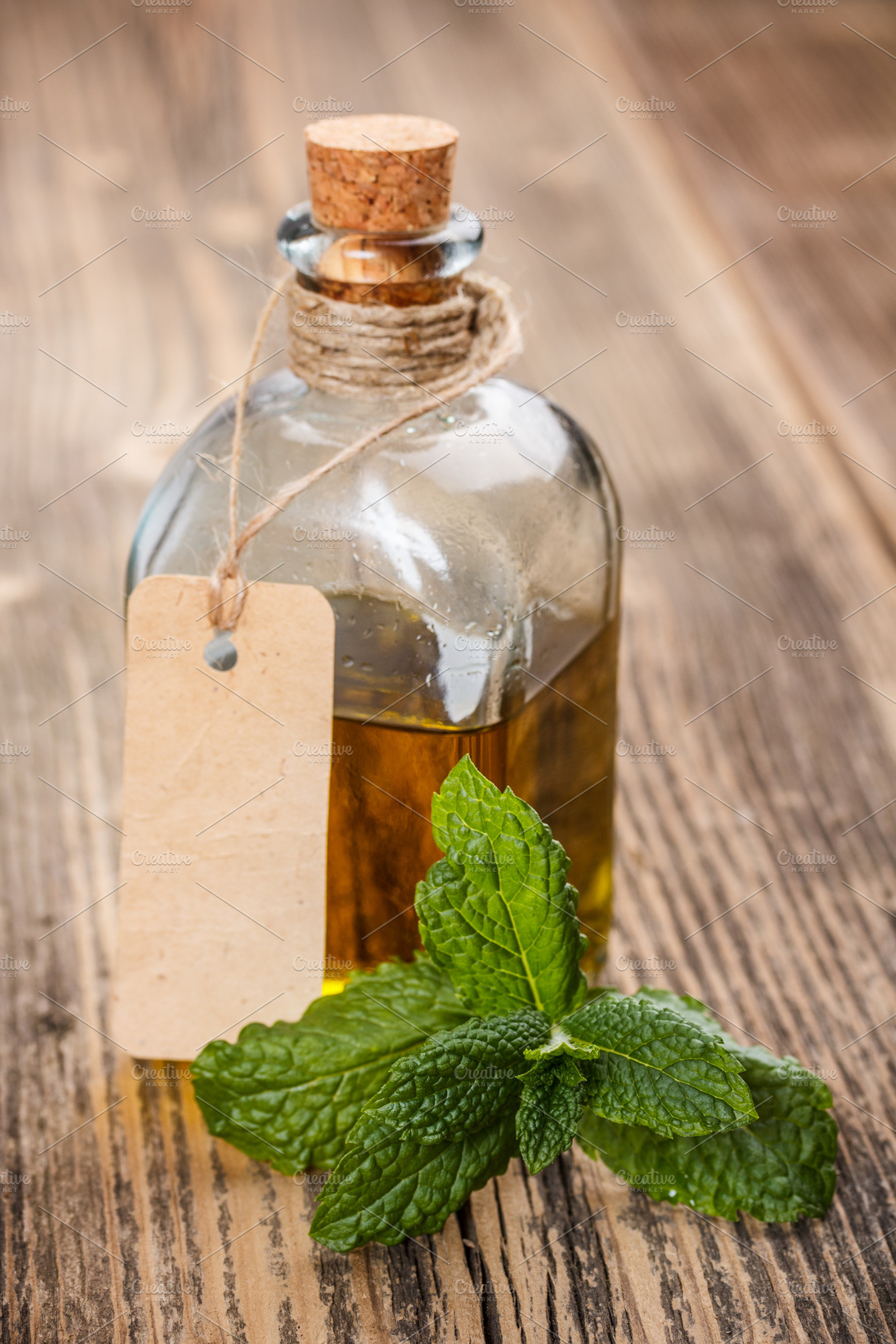 Bottle with oil containing oil, mint, and leaves
