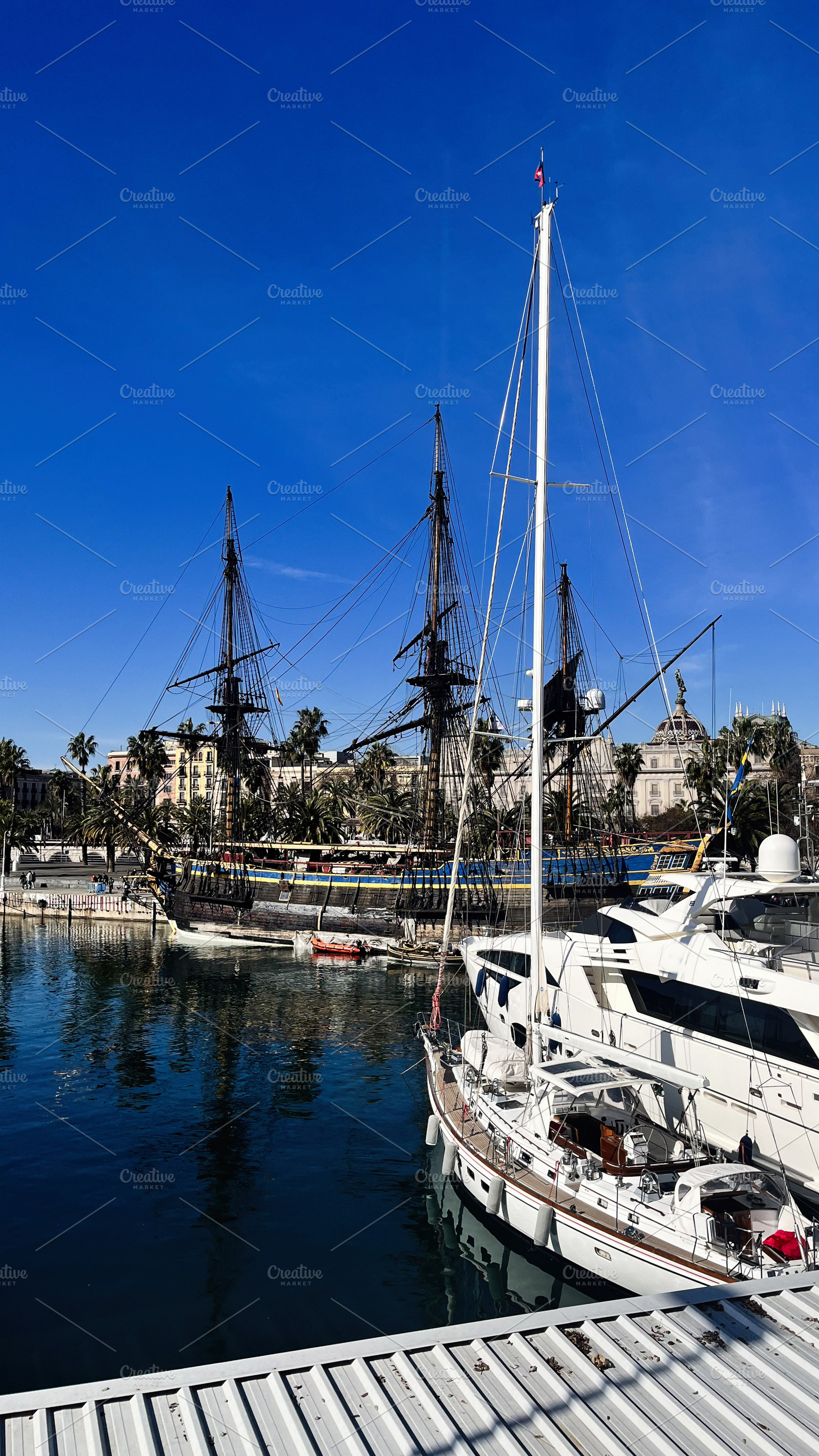 Historic wooden ships docked alongside modern yachts in scenic Barcelona, Catal, a Photo by AS photostudio