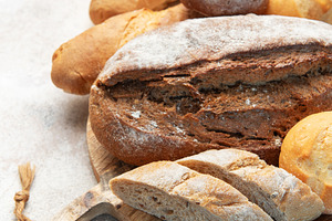 Assortment of fresh baked bread on rustic wooden board, a Food & Drink Photo by Olena Rudo