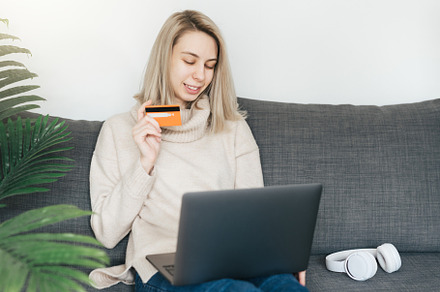 Young woman holding credit card and using laptop computer., a Person Photo by Olena Rudo