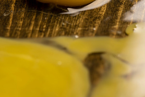 cracked chicken egg spreads on a black wooden board, side view, a Photo by rsoollAI