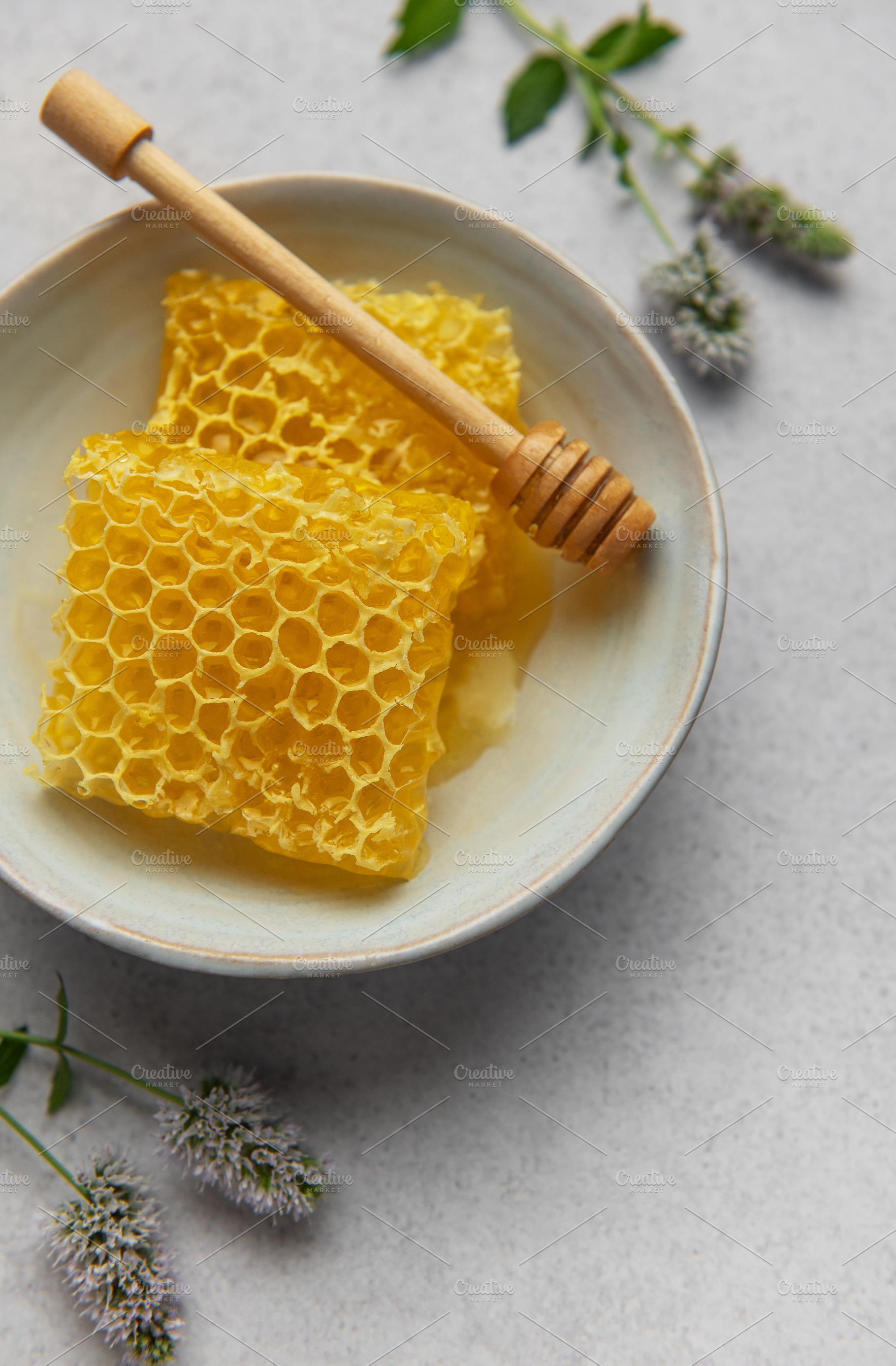 Honeycomb and honey dipper resting in bowl with fresh mint sprig, a Food & Drink Photo by Olena Rudo