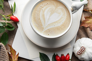 Warm autumn coffee with latte art and pumpkins