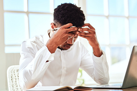 Headache, stress and businessman with burnout from work problem in office. Sad and tired corporate African employee with anxiety and depression while working on a project on internet with a laptop, a Photo by Peopleimages.com