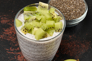 Glass of chia seed pudding mixed with diced kiwi is on a black s, a Food & Drink Photo by ndanko