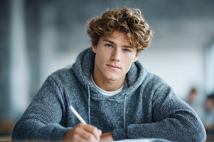 Focused student studies and writes in classroom setting