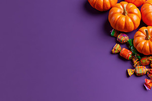 Halloween pumpkins and candy on purple copy space