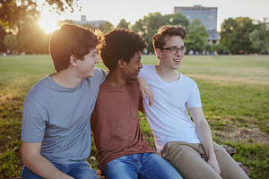 Three friends laughing together on park bench, a Photo by DanFLCreativo