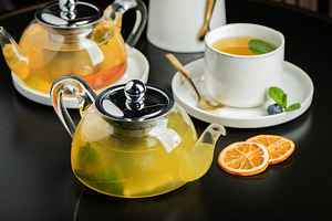 Fruit tea with mango and mint in a glass teapot on the table, a Food & Drink Photo by Budarinphoto