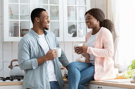 Cheeful African American Spouses Drinking Coffe In Cozy Kitchen, a Photo by Prostock-Studio