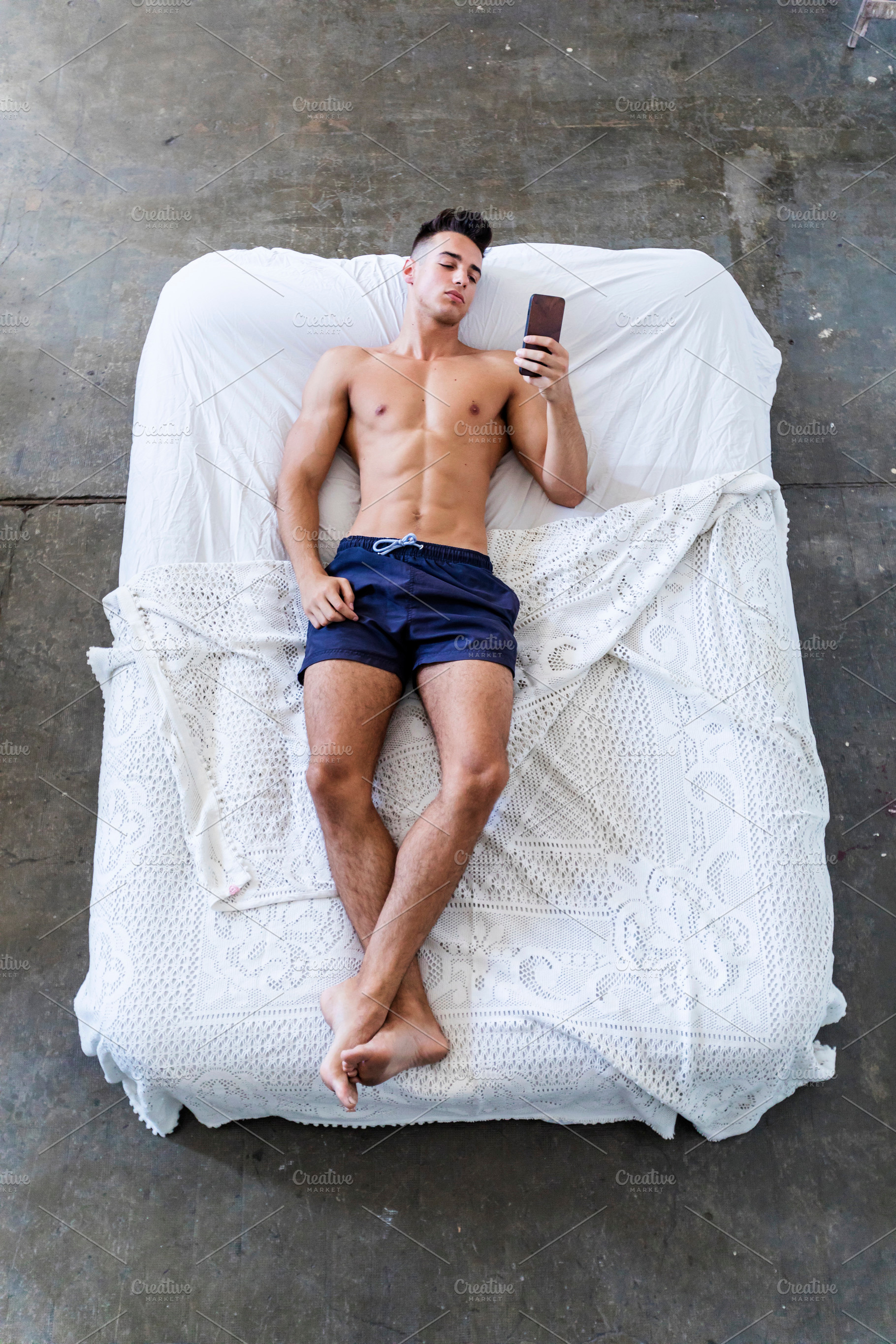 Young man relaxing in bed while using smartphone at home, a Person Photo by RF Images