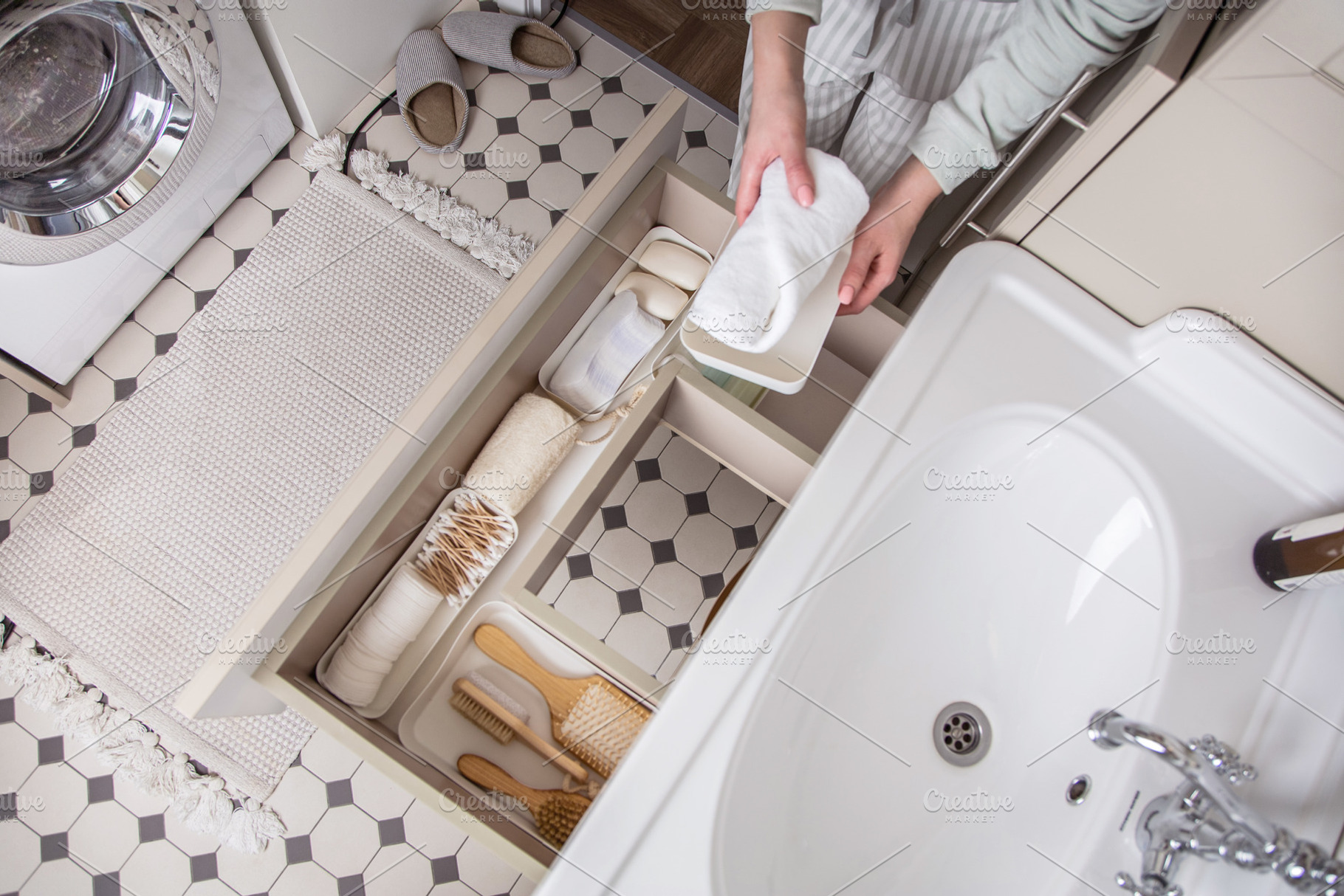 Housewife hands putting rolled up towel into drawer under sink., a Person Photo by Natalia Kostikova