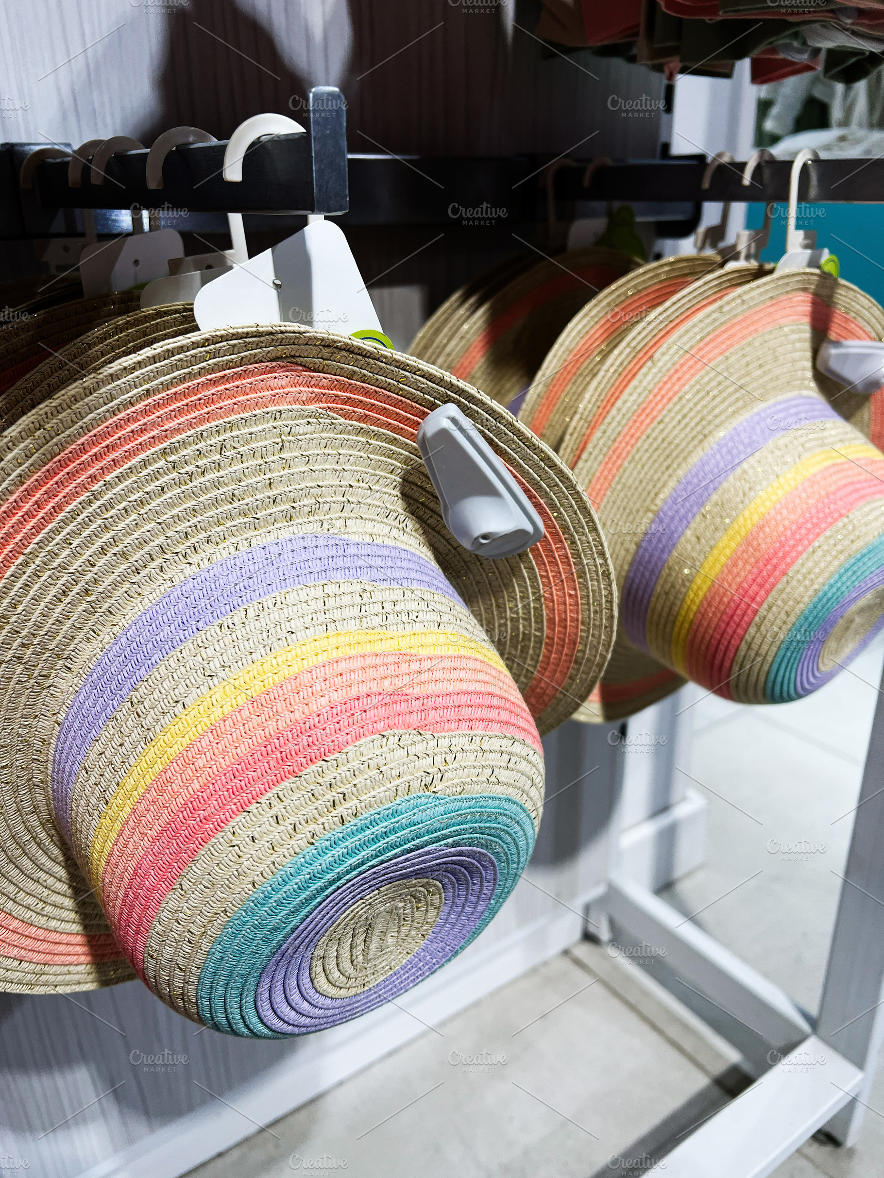Colorful wide brim hats hung on a display rack in a retail store, a Photo by AS photostudio