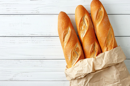 Freshly baked baguette in paper bag on wooden table, a Food & Drink Photo by AlyaAnd