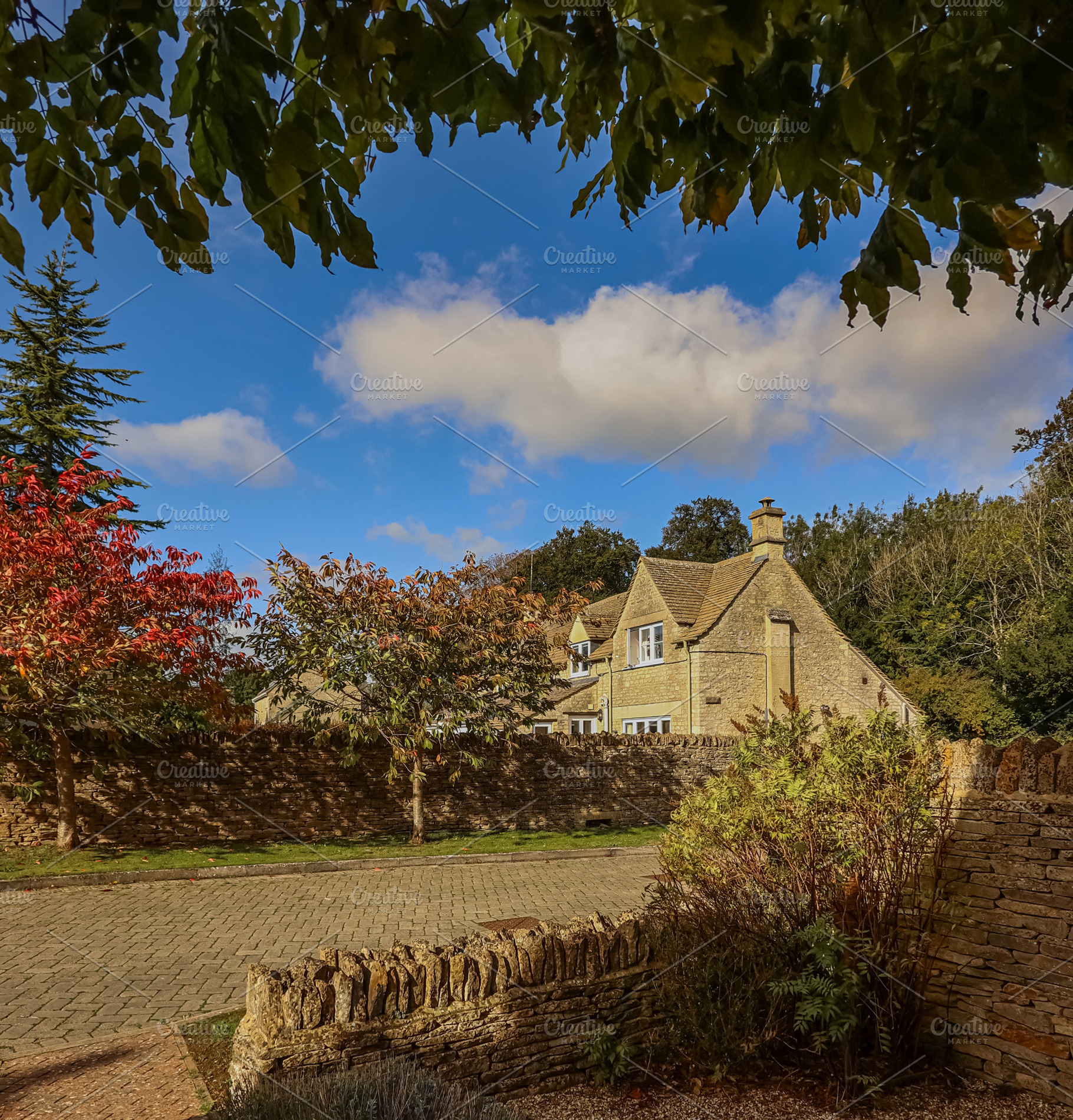 Traditional English stone cottage surrounded by autumn foliage and dry stone wa, a Photo by Studio ANNA